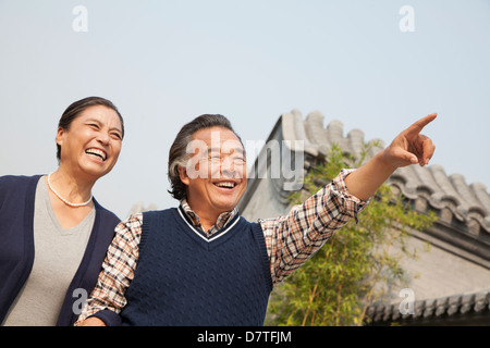 Happy senior couple outdoors pointing by traditional building in Beijing Stock Photo