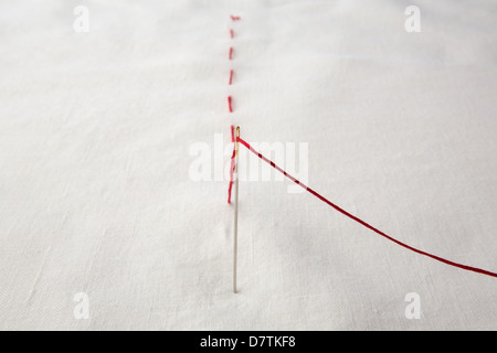 Red thread stitched on white linen. Stock Photo