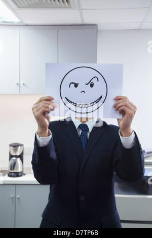 Businessman Holding Happy Face on Paper Over Face Stock Photo