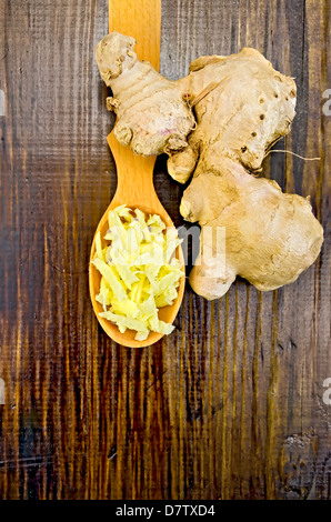 Wooden spoon with grated ginger, ginger root on a dark wooden board Stock Photo