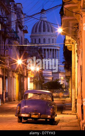 Vintage American car parked on floodlit street with The Capitolio in the background, predawn, Havana Centro, Cuba, West Indies Stock Photo