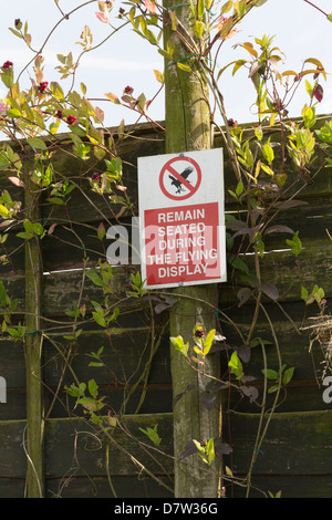 Sign asking spectators to remain seated during the flying displays at the Gauntlet Birds of Prey Eagle and Vulture Park. Stock Photo