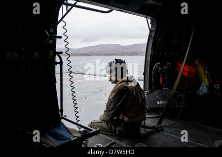 Landing onto the flight deck of HMS Bulwark in a Royal Navy Sea King Mk 4 Helicopter with the aircrewman guiding the pilot. Stock Photo