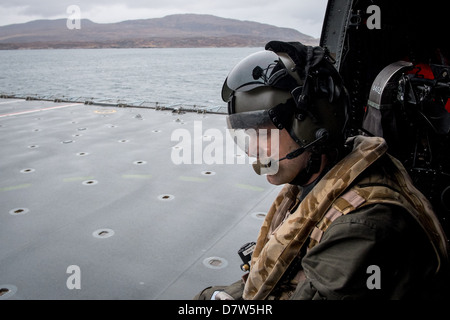 Landing onto the flight deck of HMS Bulwark in a Royal Navy Sea King Mk 4 Helicopter with the aircrewman guiding the pilot. Stock Photo