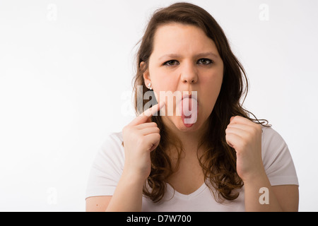A young brunette teenage Caucasian girl checking her face and complexion sticking out her tongue Stock Photo