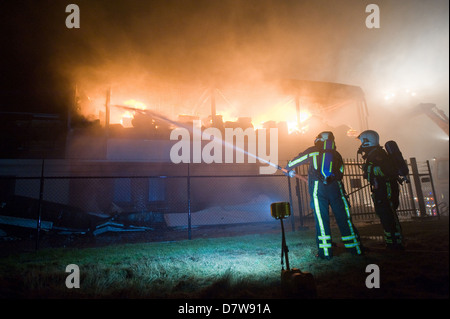 Two firefighters are trying to extinguish a fire in a building Stock Photo