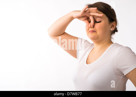 A young brunette teenage Caucasian girl pinching holding her nose to keep out a bad smell odour Stock Photo