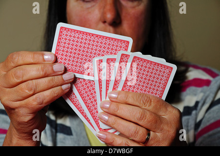 Woman choosing a card to play out of hand, England, UK, Western Europe. Stock Photo