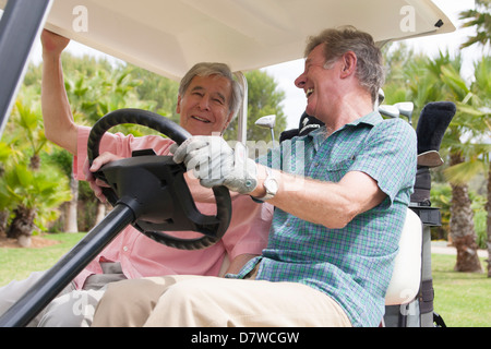 Two elderly men having a laugh on a golf buggy Stock Photo