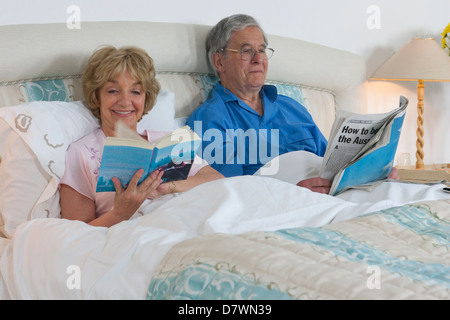 Elderly couple reading in their bed Stock Photo
