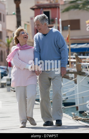 Elderly couple walking in a fishing harbour Stock Photo