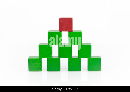 Pyramid made of green wooden blocks with a red one on top. Stock Photo