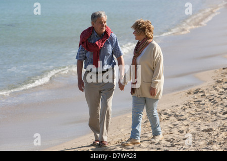 Elderly couple walking on the beach Stock Photo