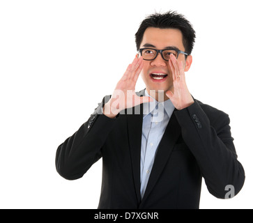 Young Asian business man shouting with hands cupped to his mouth, isolated on white background Stock Photo