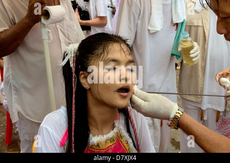 PHUKET, THAILAND OCTOBER 3 2011: A Ma Song endures the pain of a skewer extraction at the annual Phuket Vegetarian Festival. Stock Photo