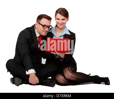 Young business couple looking together to the notebook while sitting against a white background. Stock Photo