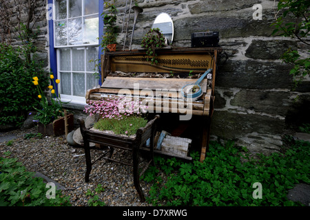 Broken piano used in a garden as a display sculpture in Machynlleth,Wales Stock Photo