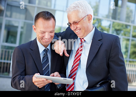 Two happy business men working together on a tablet computer Stock Photo