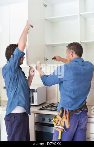 Workers installing cabinets in kitchen Stock Photo