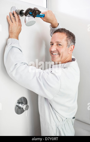 Plumber working on shower head in bathroom Stock Photo