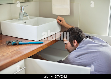 Plumber working under kitchen sink Stock Photo