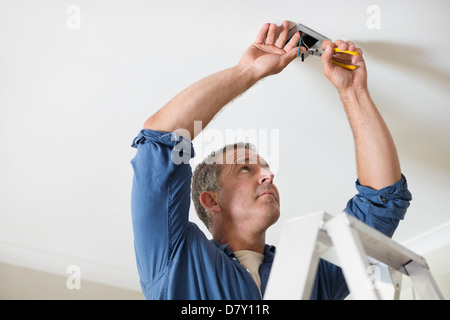 Electrician working on ceiling lights Stock Photo