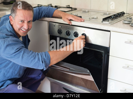 Electrician working on oven in kitchen Stock Photo