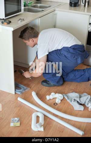 Plumber working on pipes in kitchen Stock Photo