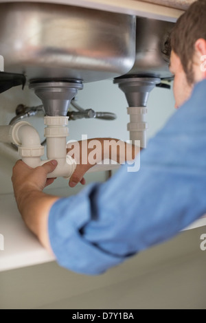 Plumber working on pipes under sink Stock Photo