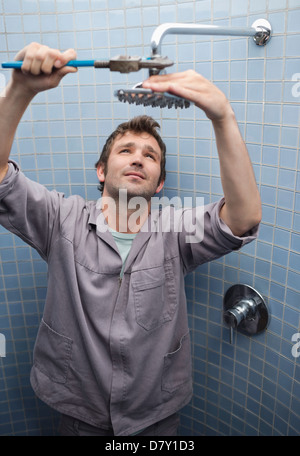 Plumber working on shower head in bathroom Stock Photo