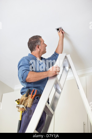 Electrician working on ceiling lights Stock Photo