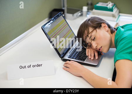Businesswoman sleeping on ‘out of order’ laptop Stock Photo