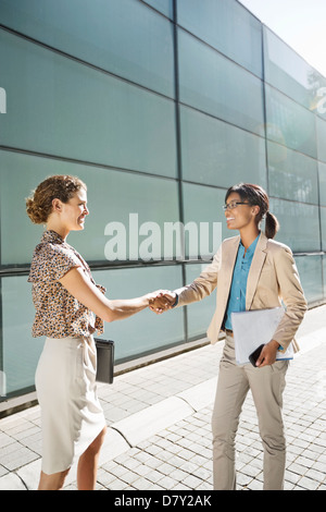 Businesswomen shaking hands on city street Stock Photo