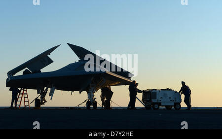 US Navy sailors move the X-47B Unmanned Combat Air System aircraft to the flight deck for launch on the aircraft carrier USS George H.W. Bush May 14, 2013 in the Atlantic Ocean. The George H.W. Bush is the first aircraft carrier to successfully catapult launch an unmanned aircraft from its flight deck. Stock Photo