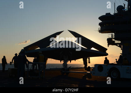 US Navy sailors move the X-47B Unmanned Combat Air System aircraft to the flight deck for launch on the aircraft carrier USS George H.W. Bush May 14, 2013 in the Atlantic Ocean. The George H.W. Bush is the first aircraft carrier to successfully catapult launch an unmanned aircraft from its flight deck. Stock Photo
