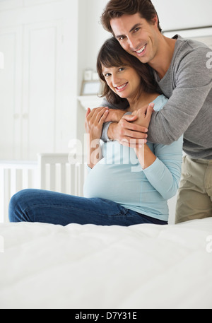 Man hugging pregnant girlfriend on bed Stock Photo