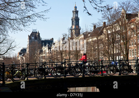 Cyclist on bridge, on Keizersgracht, Grachtengordel-west, Jordaan, central Amsterdam, Netherlands. Westerkerk tower beyond. Stock Photo