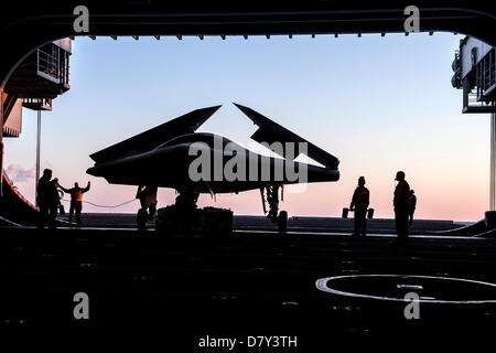 US Navy sailors move the X-47B Unmanned Combat Air System aircraft on the elevator for launch from the flight deck of the aircraft carrier USS George H.W. Bush May 14, 2013 in the Atlantic Ocean. The George H.W. Bush is the first aircraft carrier to successfully catapult launch an unmanned aircraft from its flight deck. Stock Photo