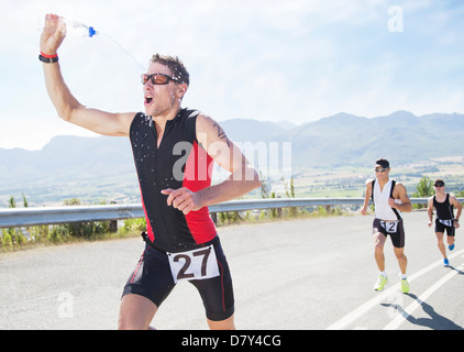 Runner spraying himself with water in race Stock Photo