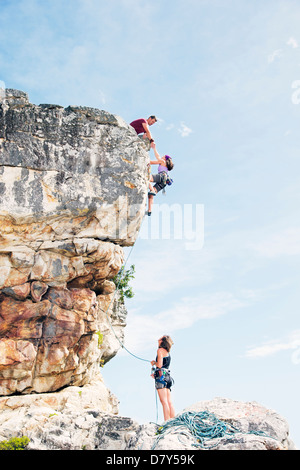 Climbers scaling steep rock face Stock Photo