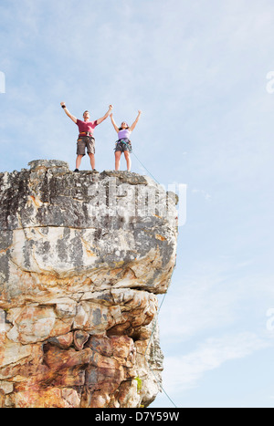 Climbers cheering on rocky cliff Stock Photo