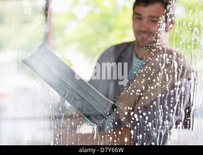Man washing windows with squeegee Stock Photo