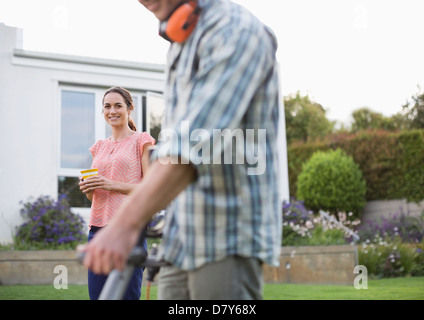 Woman watching man work in garden Stock Photo