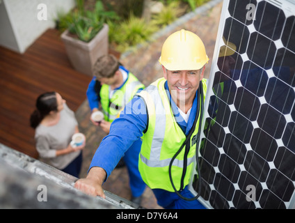 Worker installing solar panel on roof Stock Photo