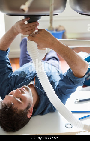 Plumber working on pipes under sink Stock Photo