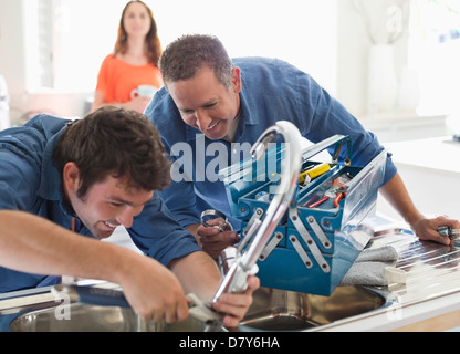 Plumbers working on kitchen sink Stock Photo
