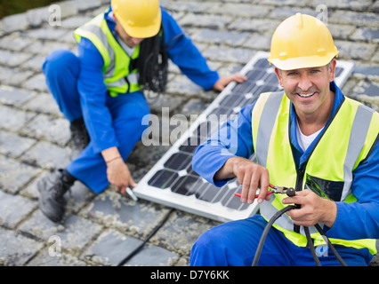 Workers installing solar panel on roof Stock Photo