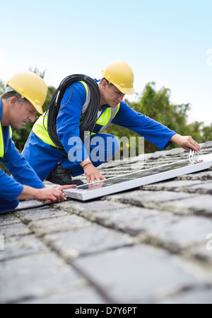 Workers installing solar panels on roof Stock Photo