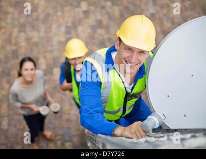 Workers installing satellite dish on roof Stock Photo