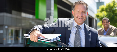 Businessman climbing out of car Stock Photo